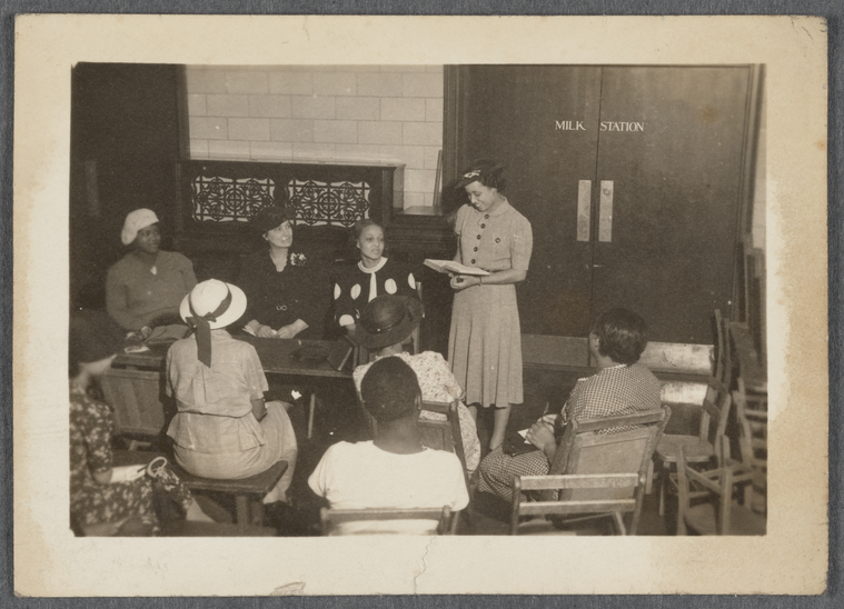 Woman standing with book surrounded by young people